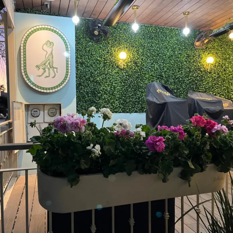 Jardineras con flores y muro verde en la terraza de un restaurante