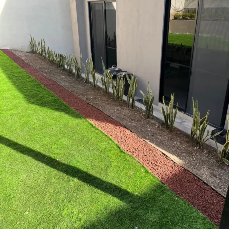 Jardín exterior de una oficina con pasto y franja de grava roja